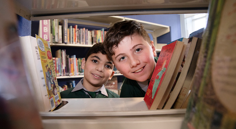 St Patrick's Catholic Primary School Parramatta students peering through library book shelf