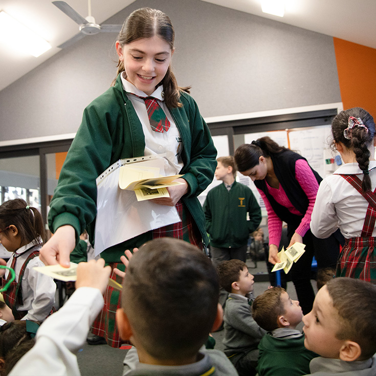 St Patrick's Catholic Primary School Parramatta student leader passing paper out to younger children